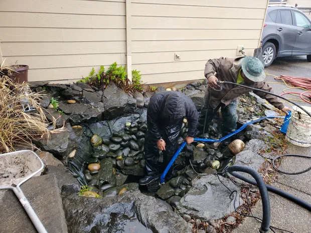 Crew pressure-washing rock and gravel during a full pond cleanout